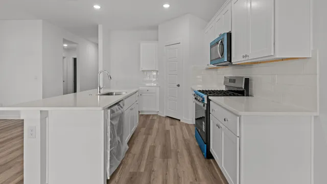 a kitchen with white cabinets sink and stove