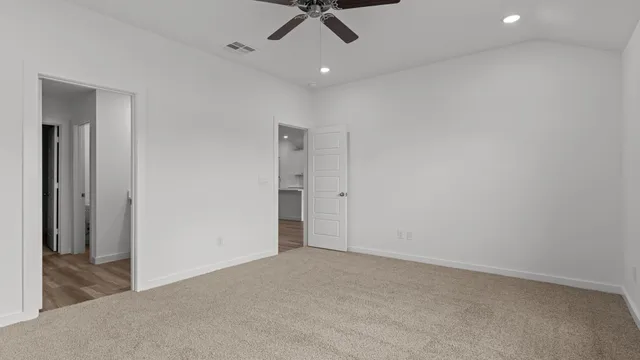 an empty room with a ceiling fan and carpet