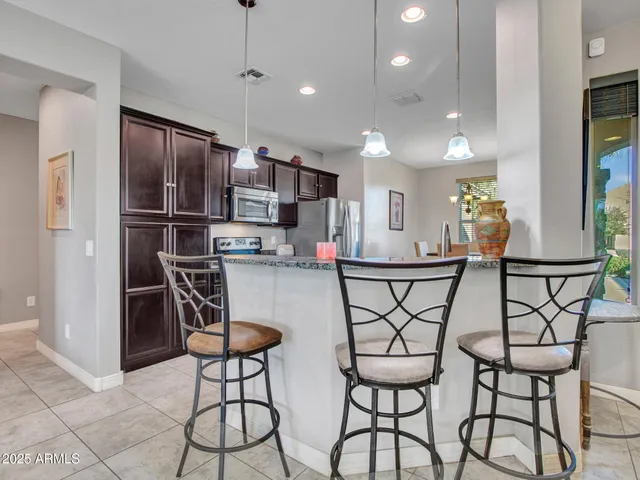 a kitchen with stainless steel appliances kitchen island granite countertop a dining table chairs and a refrigerator
