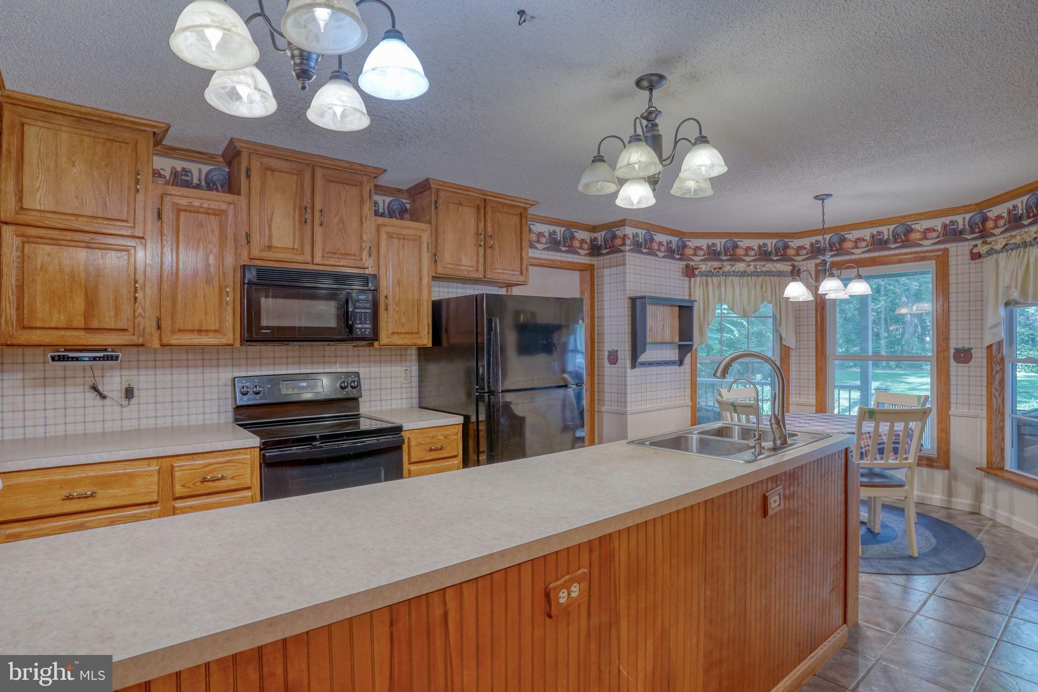 1332 Alley Mill Road Clayton, DE 19938 - Photo 25 of 50 a large kitchen with stainless steel appliances granite countertop a sink dishwasher stove top oven a refrigerator with wooden floor and cabinets