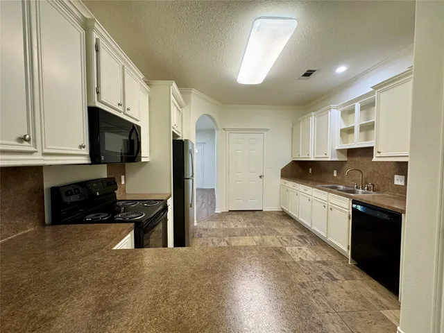 a kitchen with granite countertop a stove top oven a sink a counter space and cabinets
