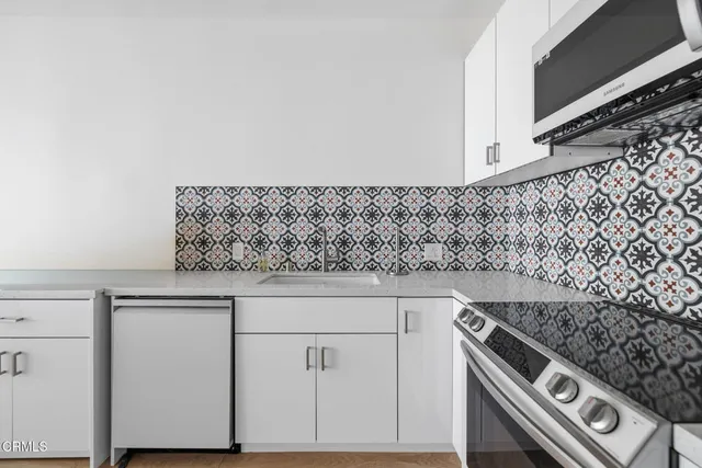 a view of kitchen and empty room with wooden floor