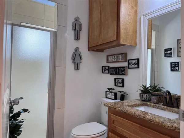a bathroom with a granite countertop sink a toilet and shower