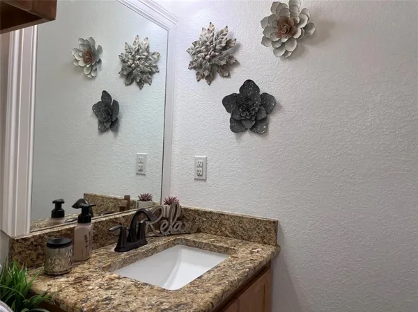 a bathroom with a granite countertop sink a mirror and vanity