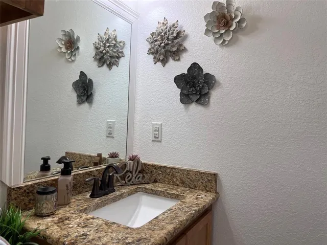 a bathroom with a granite countertop sink a mirror and vanity