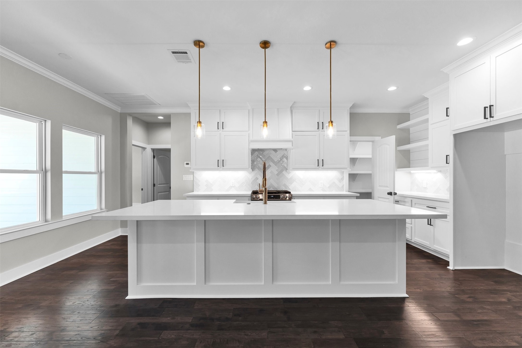 1087 Jones Road New Waverly, TX 77358 - Photo 2 of 44 Sleek modern kitchen featuring an expansive island, elegant pendant lighting, and ample white cabinetry, complemented by dark hardwood floors.