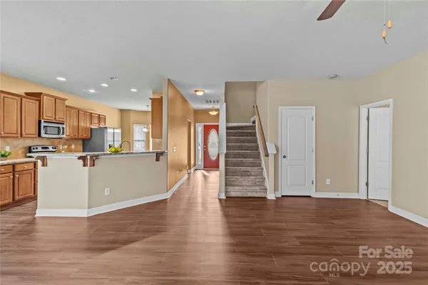 a view of kitchen with stainless steel appliances granite countertop a stove top oven a refrigerator a sink and a oven with wooden floor