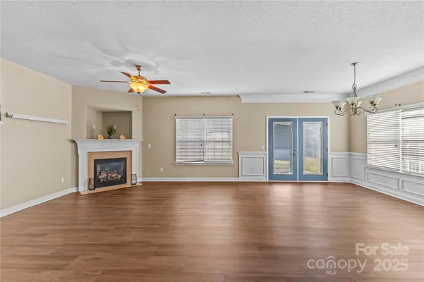 a view of an empty room with wooden floor fireplace and a window
