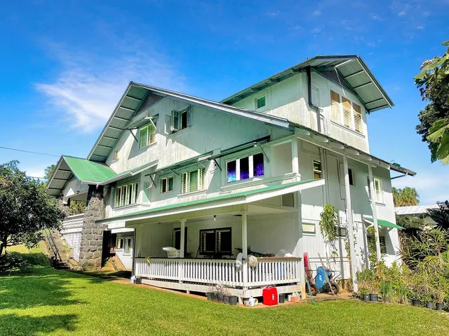 a view of a white house with large windows and a yard with table and chairs