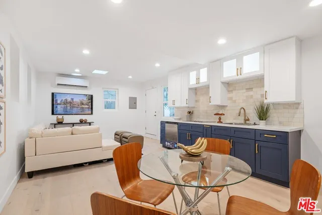 a living room with furniture a kitchen island with white cabinets and couches chair