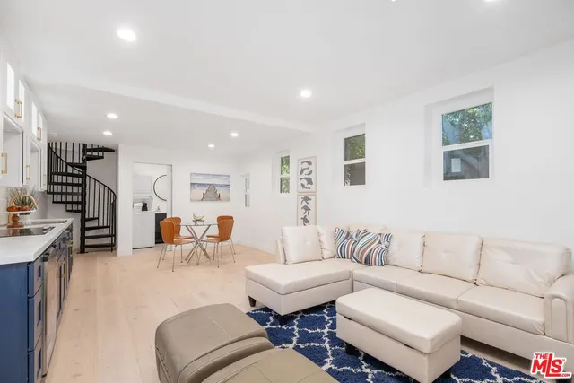 a living room with furniture kitchen view and a wooden floor
