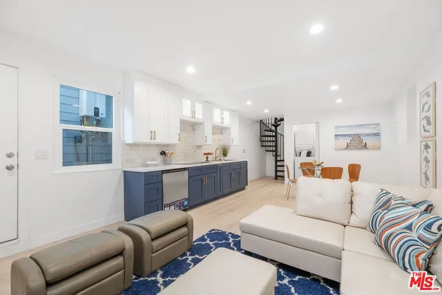 a living room with furniture kitchen view and a wooden floor