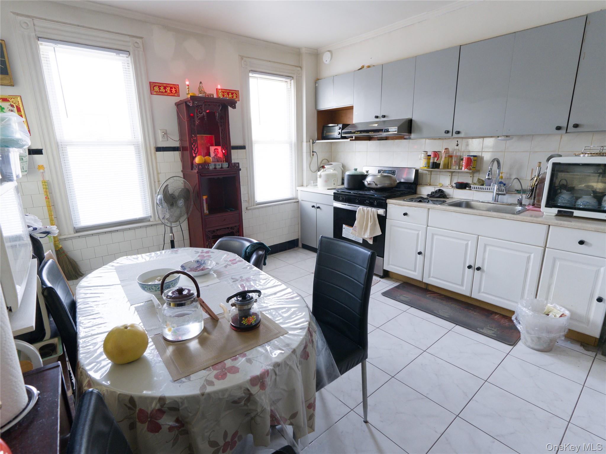 86-24 79th Street Queens, NY 11421 - Photo 10 of 31 a kitchen with stainless steel appliances kitchen island granite countertop a sink a stove a dining table and chairs