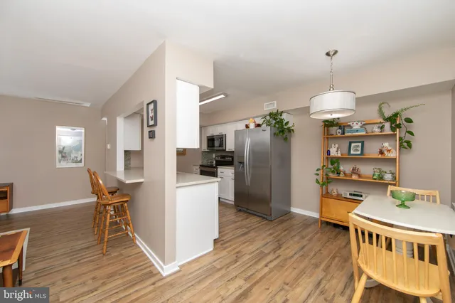 a dining room with stainless steel appliances wooden floor dining table chairs and wooden floor