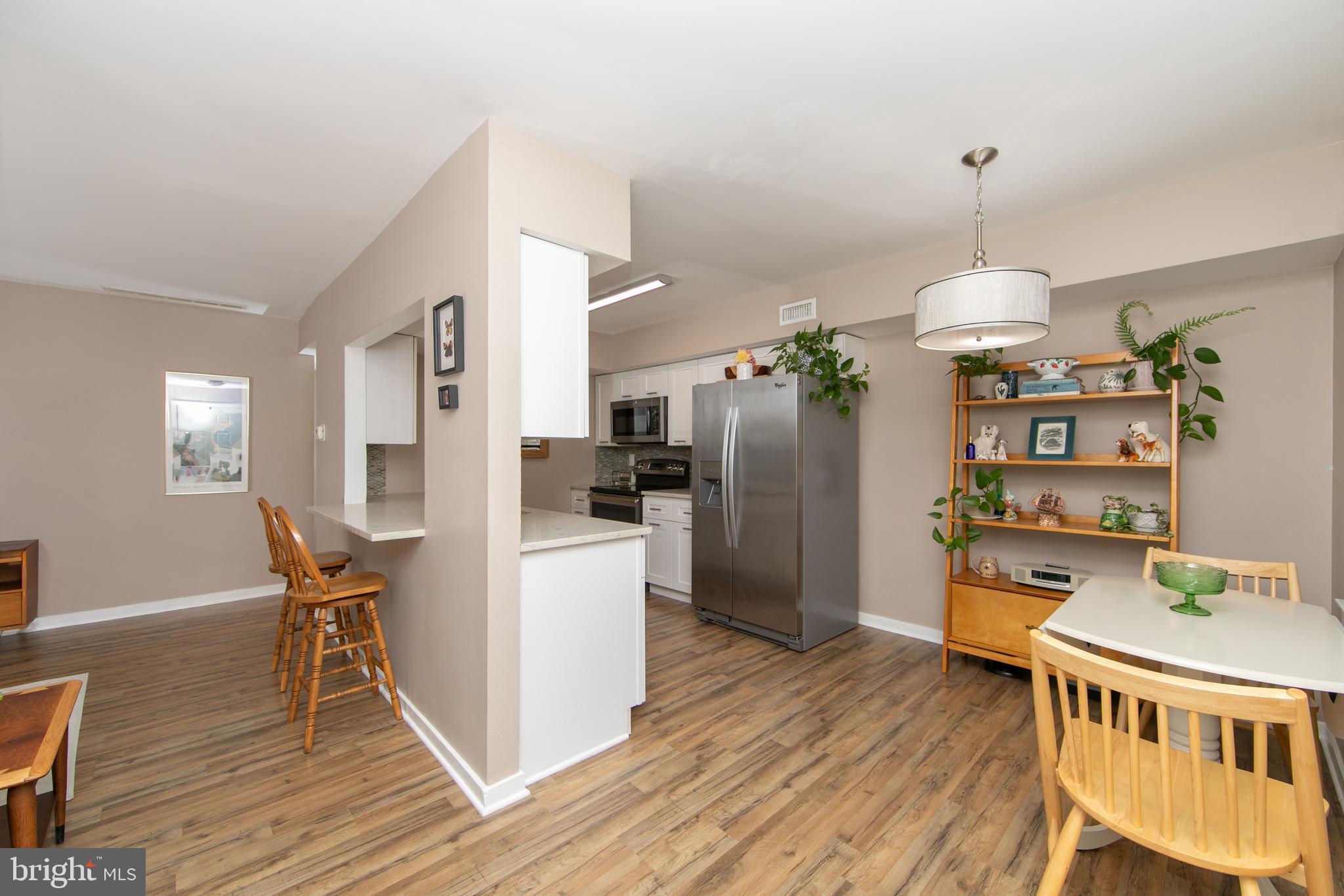 a dining room with stainless steel appliances wooden floor dining table chairs and wooden floor