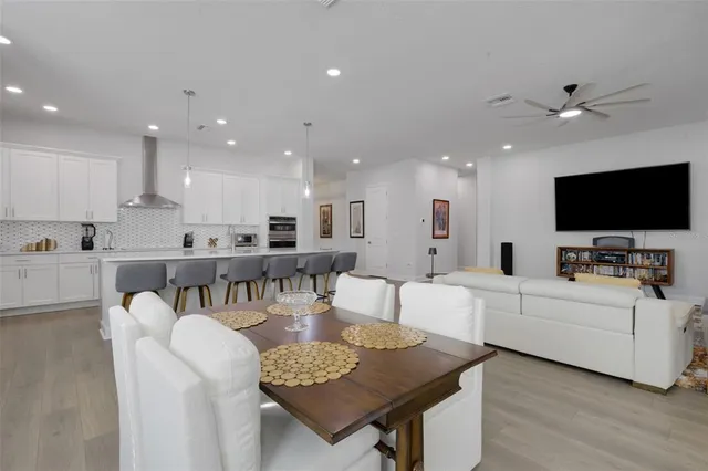 a open dining room with stainless steel appliances kitchen island granite countertop a dining table chairs and couches