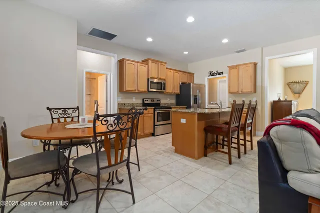 a kitchen with stainless steel appliances granite countertop a stove top oven a sink dishwasher a dining table and chairs with wooden floor