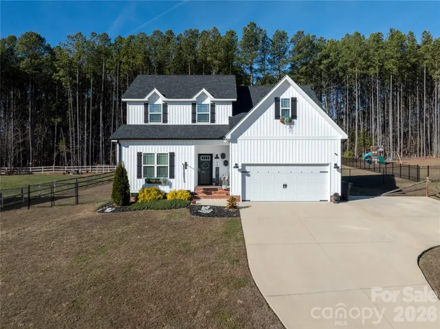 a view of a house with backyard and trees in the background