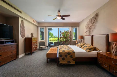 a bedroom with bed and a flat tv screen on dresser