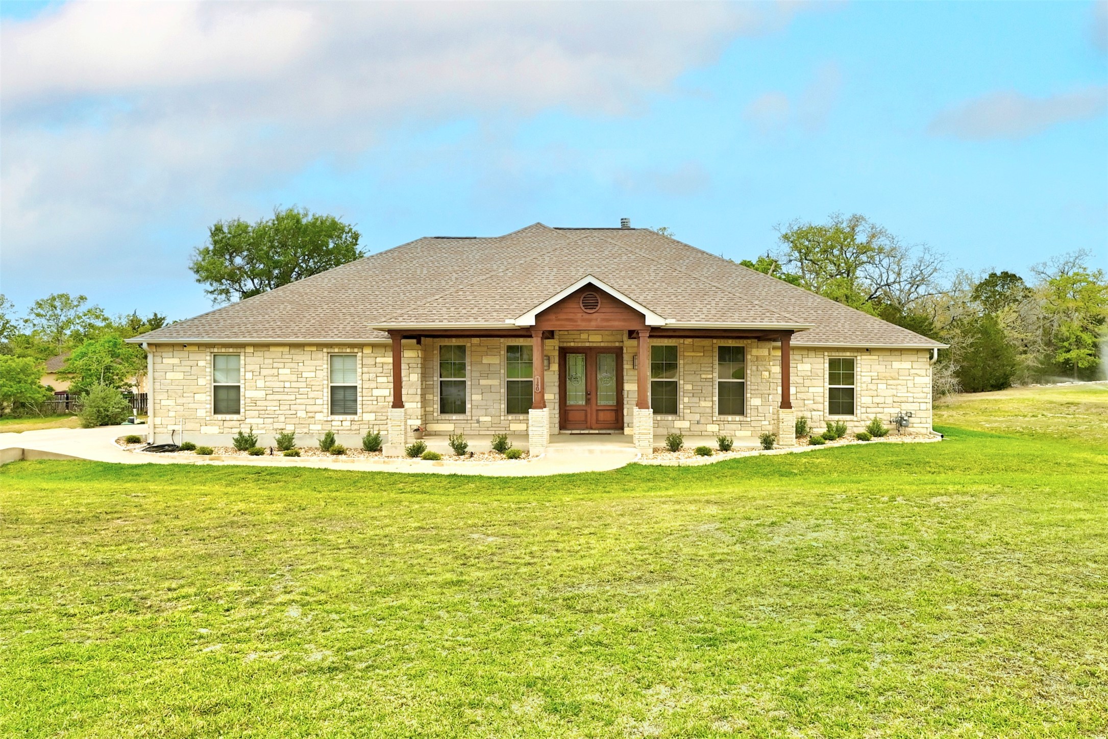 140 Winchester Road Bastrop, TX 78602 - Photo 2 of 36 View of front facade featuring stone siding, covered porch, and a front lawn