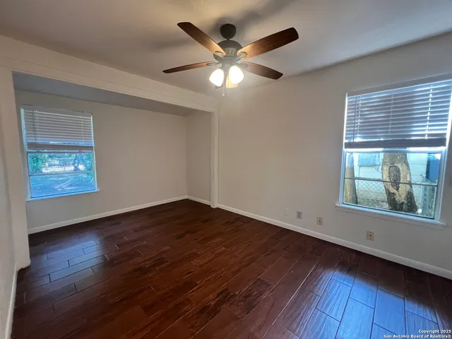 a view of an empty room with wooden floor and a window