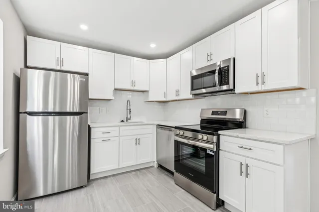 a kitchen with stainless steel appliances granite countertop white cabinets a sink a stove a refrigerator and white cabinets