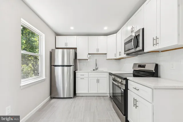 a kitchen with stainless steel appliances granite countertop white cabinets a refrigerator a stove a sink and a microwave