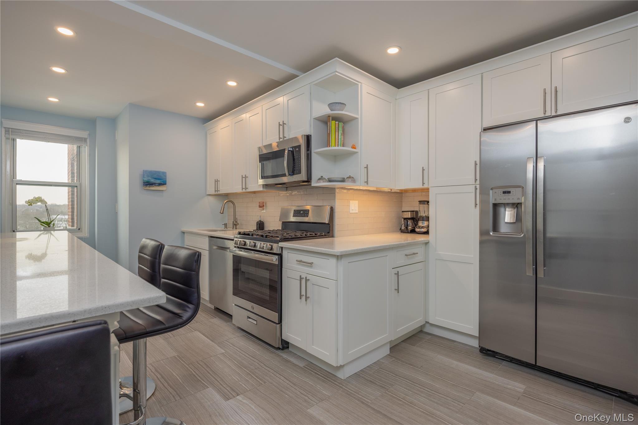 900 Palmer Road, Unit 9J Bronxville, NY 10708 - Photo 1 of 14 a kitchen with stainless steel appliances granite countertop a refrigerator a sink dishwasher a stove and white cabinets with wooden floor