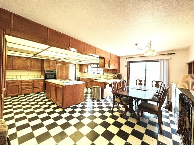 a living room with stainless steel appliances furniture a rug and a kitchen view
