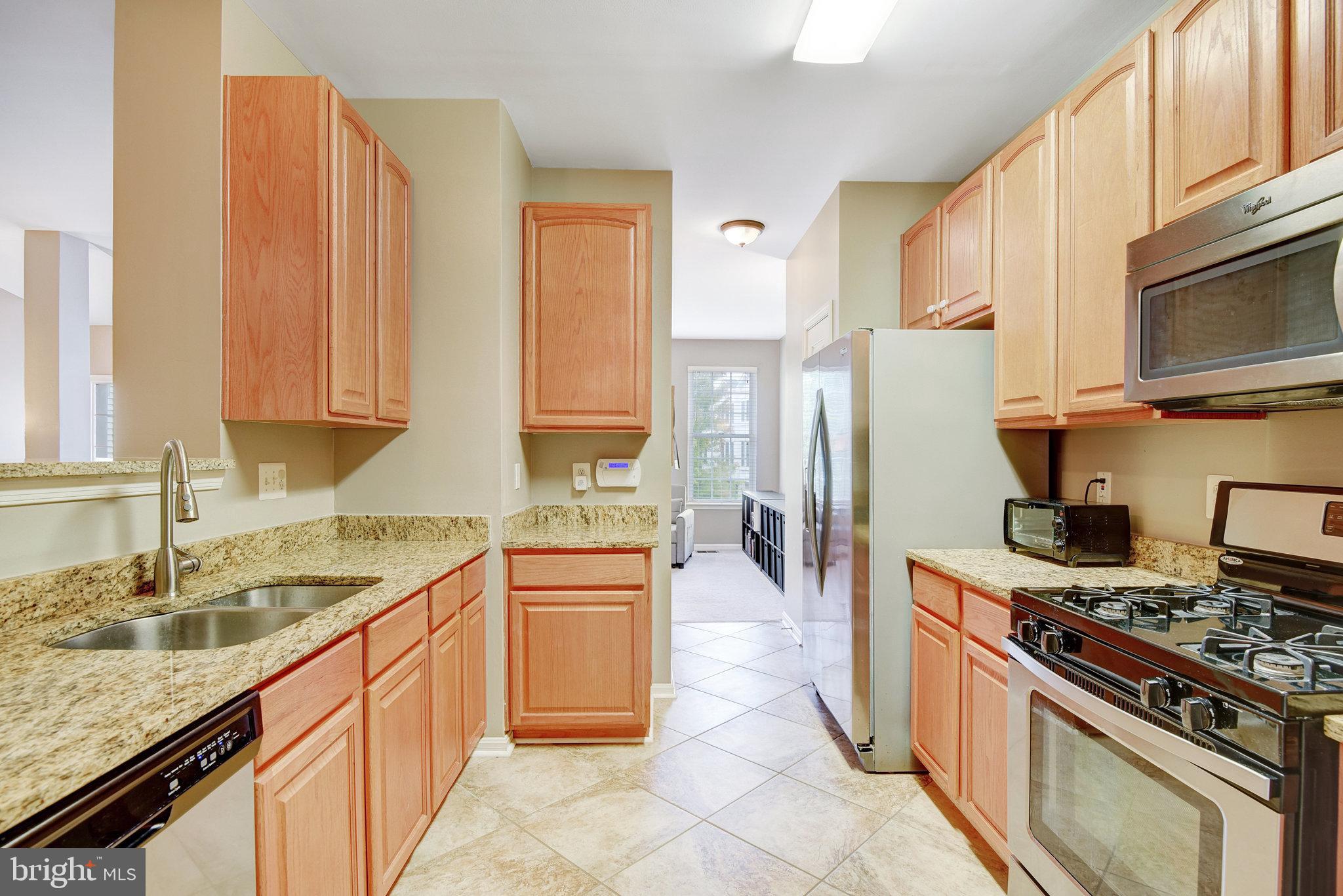 13017 Bath Gate Way Bristow, VA 20136 - Photo 13 of 35 a kitchen with stainless steel appliances granite countertop a sink stove and refrigerator