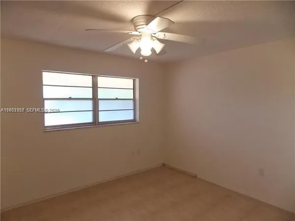 an empty room with a chandelier fan and windows