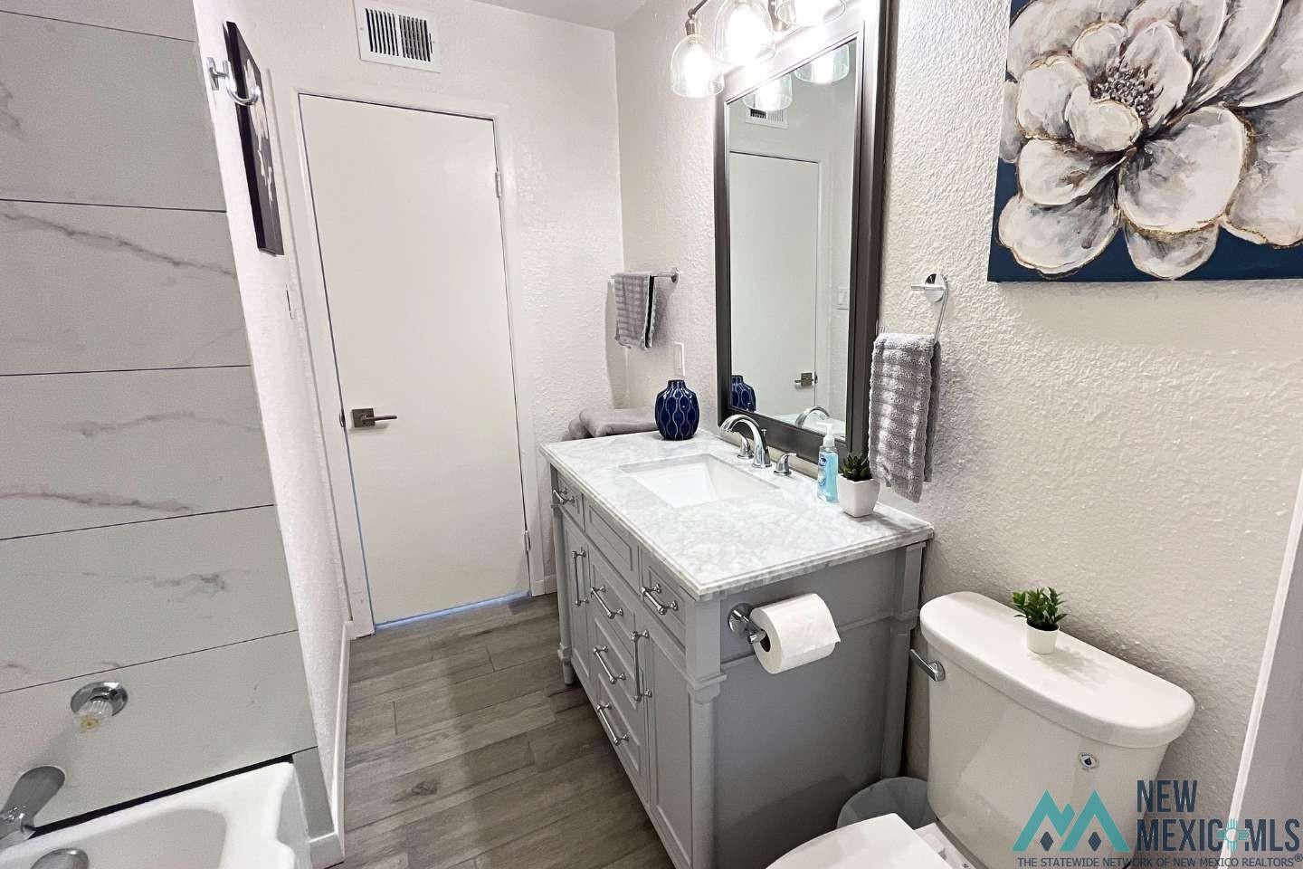 241 Junction Road Ruidoso, NM 88345 - Photo 24 of 44 Bathroom with a textured wall, vanity, wood finished floors, and shower / tub combination