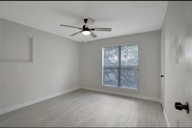 an empty room with windows and ceiling fan