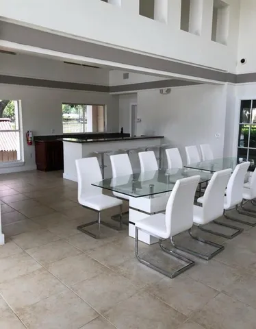 a view of a white house next to a yard with potted plants