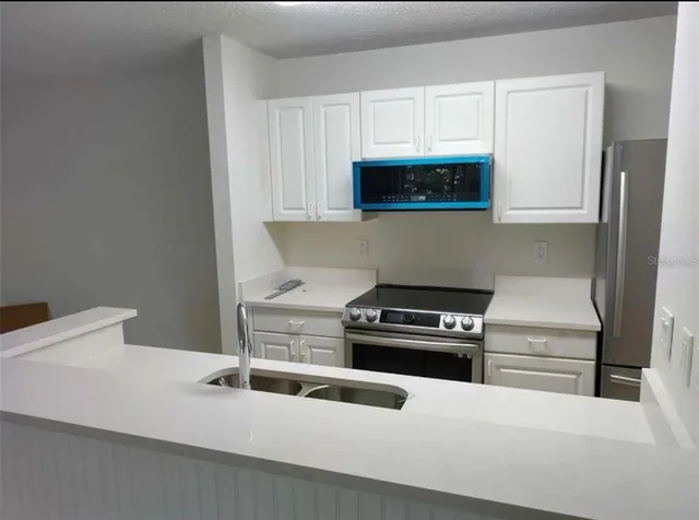 a kitchen with white cabinets and a stove with a sink