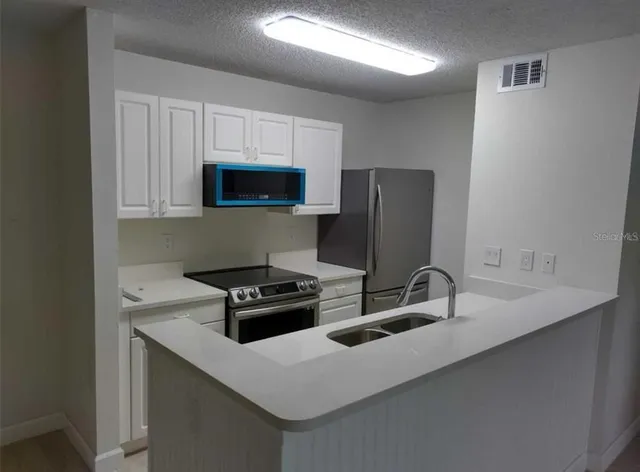 a kitchen with stainless steel appliances a stove a sink a microwave and refrigerator