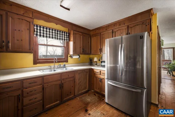 a kitchen with stainless steel appliances granite countertop a refrigerator and a wooden floors