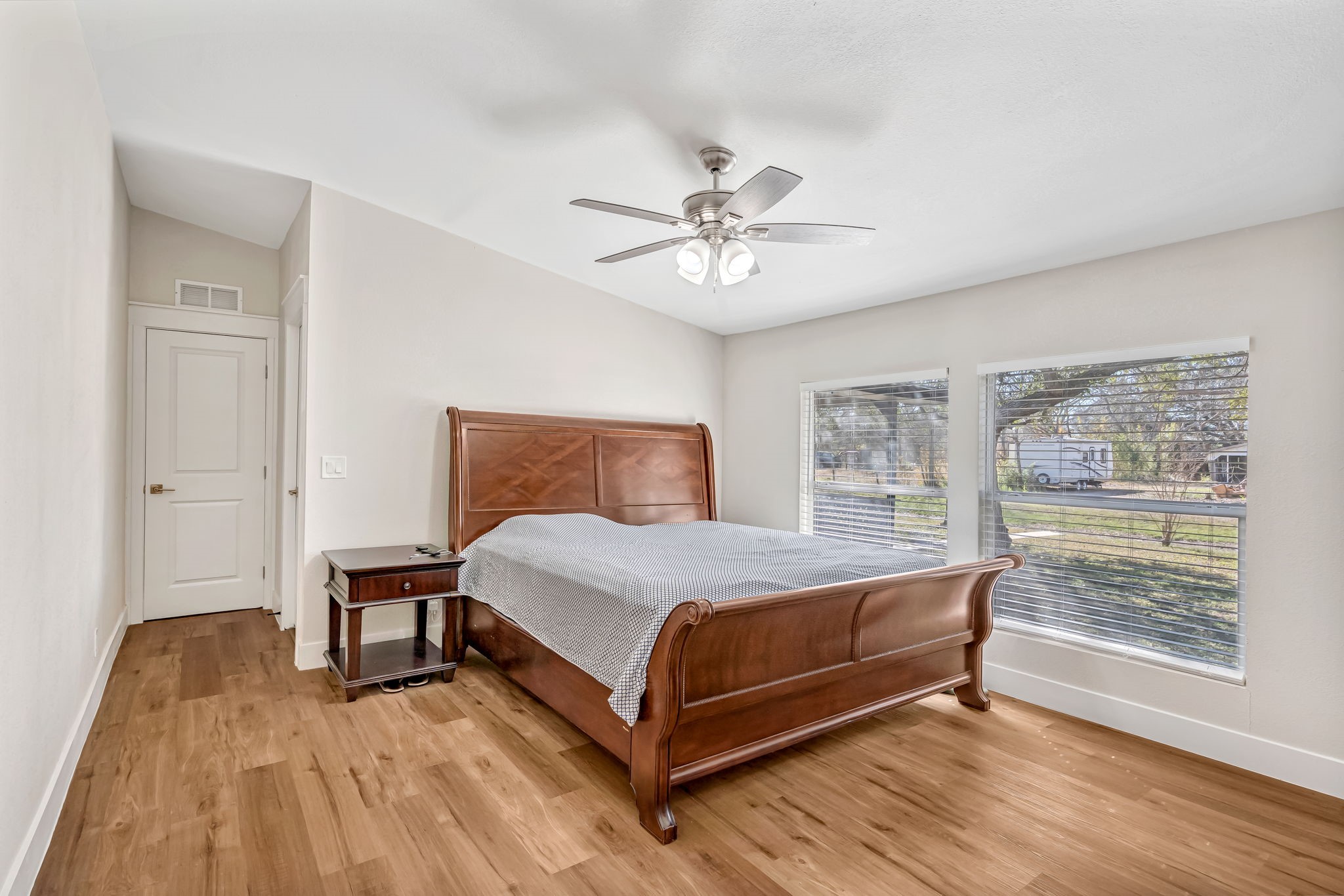 1491 Pecan Valley Road Wharton, TX 77488 - Photo 13 of 38 Bright and inviting bedroom with wood flooring, abundant natural light from two windows, and a ceiling fan for comfort. Neutral walls enhance its cozy charm.