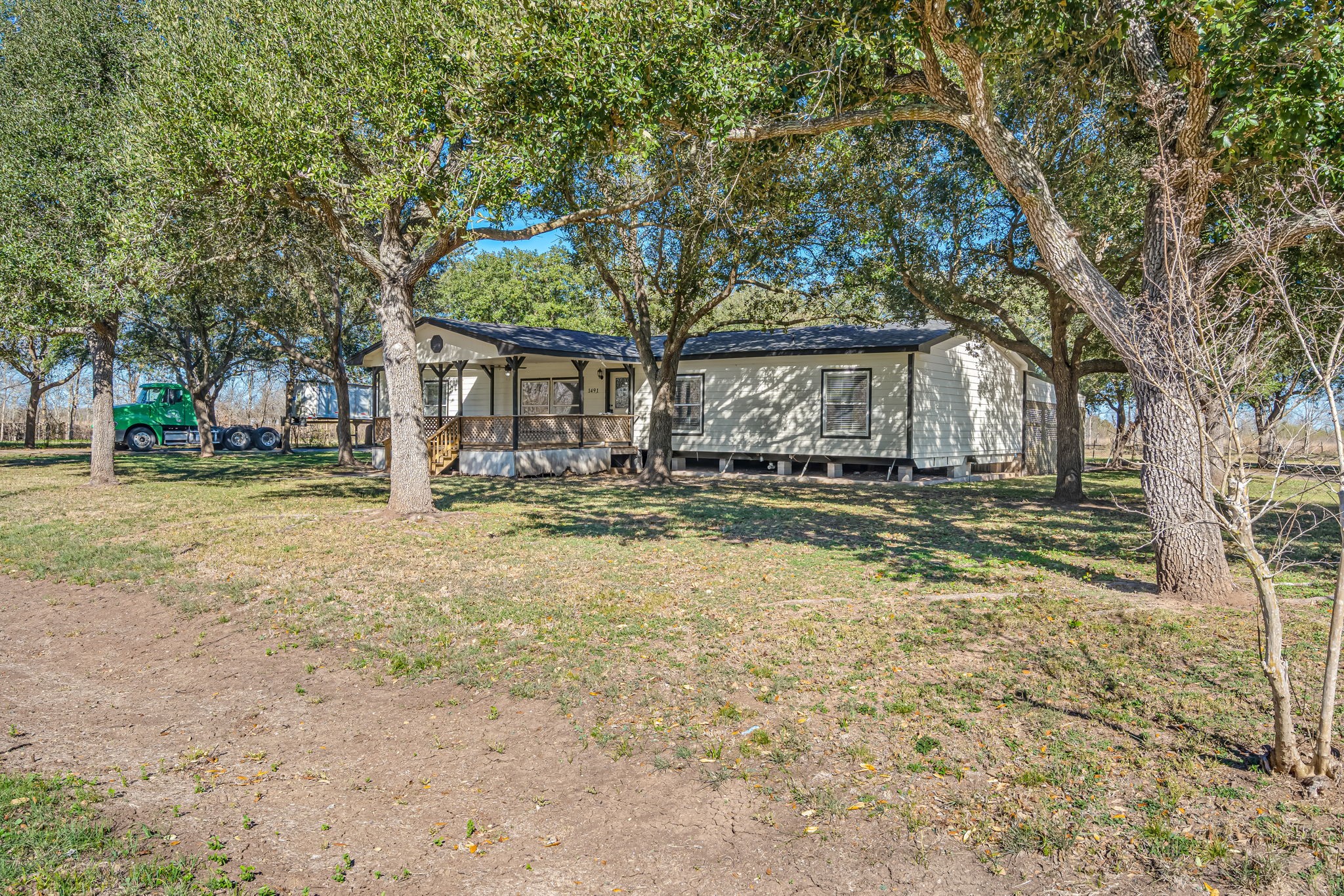 1491 Pecan Valley Road Wharton, TX 77488 - Photo 2 of 38 Discover serenity in this charming home with a spacious porch, surrounded by mature trees and an expansive yard, perfect for nature lovers.