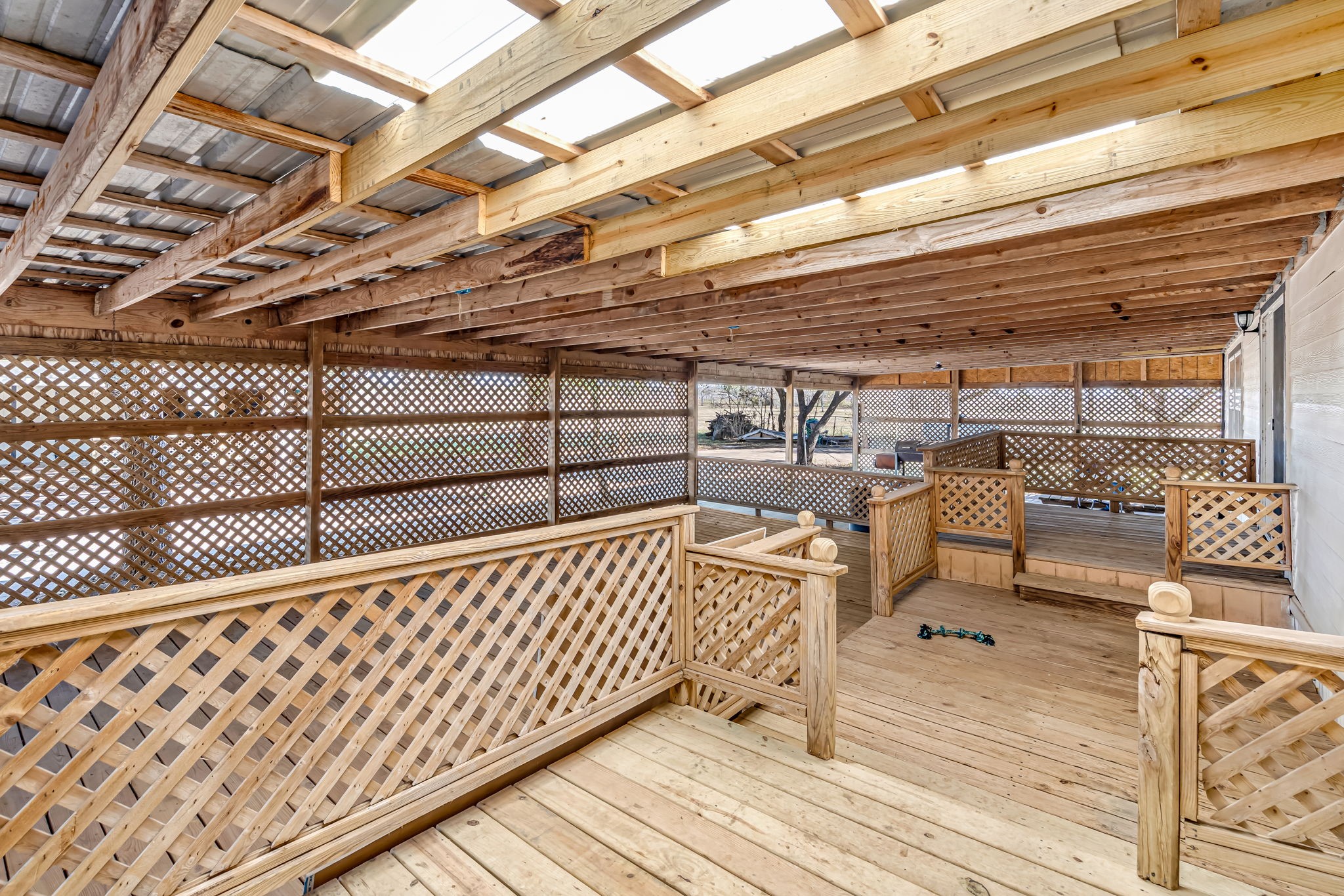 1491 Pecan Valley Road Wharton, TX 77488 - Photo 23 of 38 This inviting covered wooden patio features privacy-enhancing lattice railings and a sloped roof, perfect for relaxation or entertaining. It connects to the home.