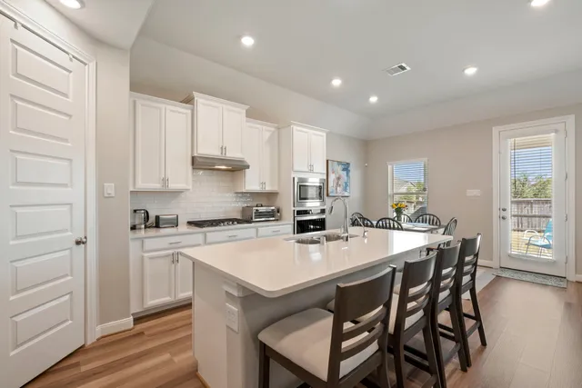 a kitchen with a dining table chairs and white cabinets