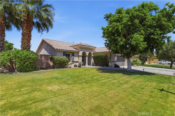a front view of a house with a garden and trees