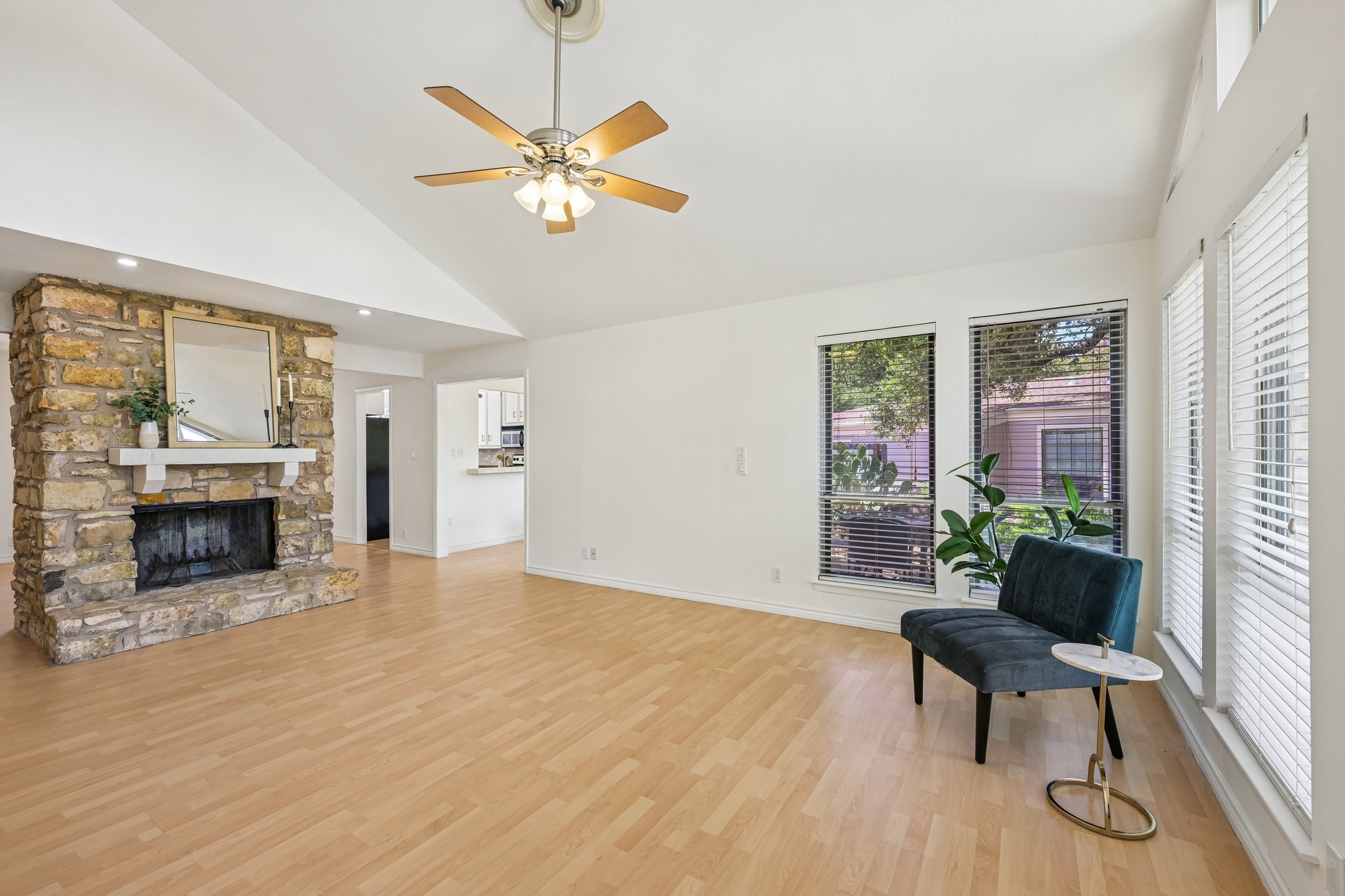 13101 Travis View Loop Austin, TX 78732 - Photo 5 of 27 A well-lit living area features a robust stone fireplace and light-toned wood-look flooring.
