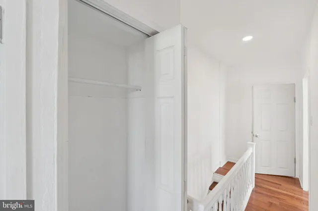 a view of an empty room with wooden floor and closet