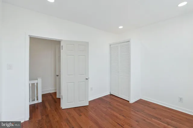 a view of an empty room with wooden floor and closet