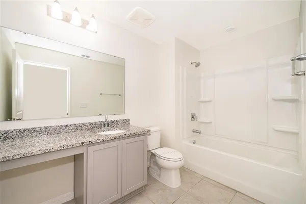 a bathroom with a granite countertop sink a toilet mirror and bathtub