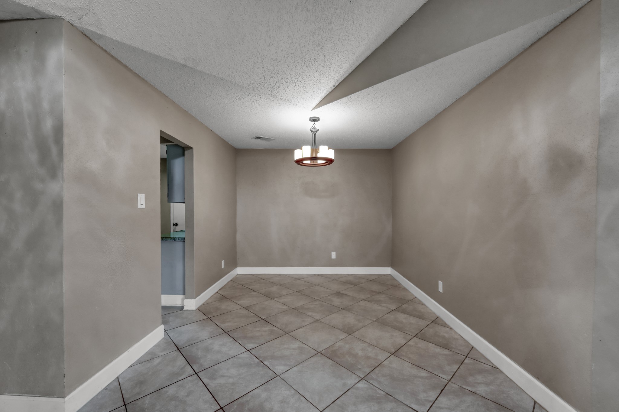 12015 Fallbrook Drive Houston, TX 77065 - Photo 9 of 29 This photo shows a dining area with neutral-toned walls and a tiled floor. It features a modern light fixture and an entryway leading to another room, creating an open feel.