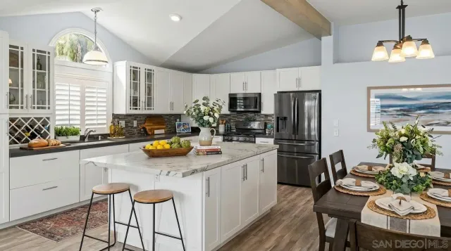 a kitchen with a refrigerator a stove a sink dishwasher a dining table and chairs with wooden floor