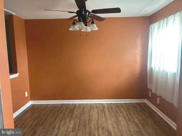 an empty room with wooden floor fan and windows