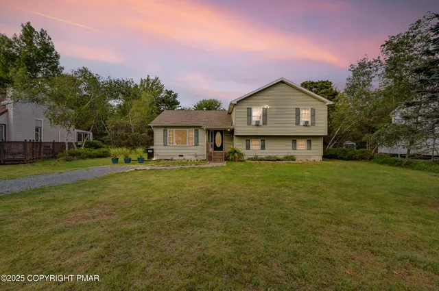 a front view of a house with a garden and trees